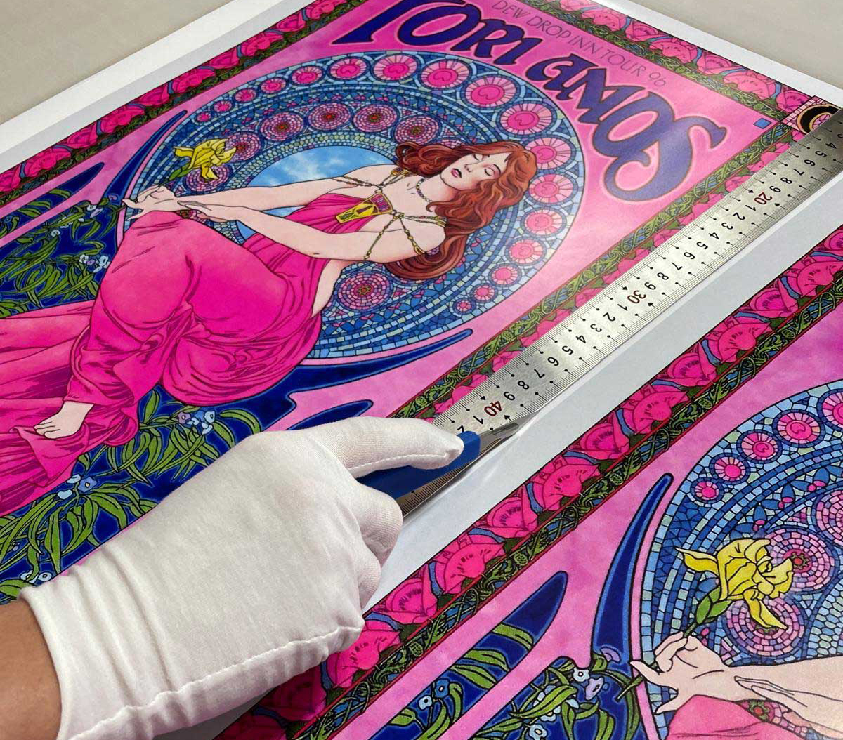 Fine art poster being hand-trimmed with cotton gloves and steel ruler